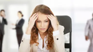 Worried female CEO sitting at her desk, stressed and overwhelmed, representing the hidden toxic culture infecting companies.