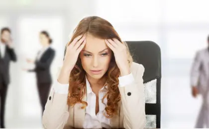 Worried female CEO sitting at her desk, stressed and overwhelmed, representing the hidden toxic culture infecting companies.